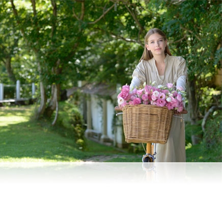Nikon D610 photo of a woman in a garden with flowers in a basket on her bicycle